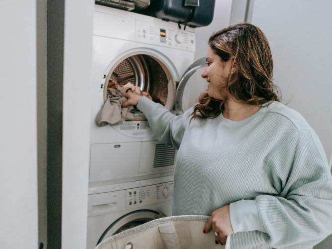 Image of a woman loading a washing machine