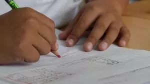 A child drawing in pencil in a notebook