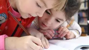 Two children writing in a school book.