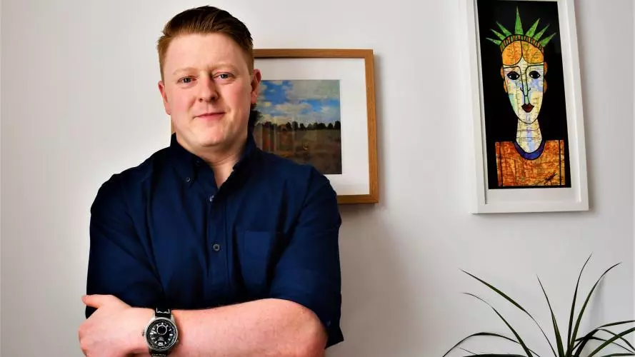 Lucas Bunnetat stands in front of two paintings
