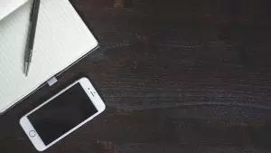 Lined notepad and pen next to iPhone