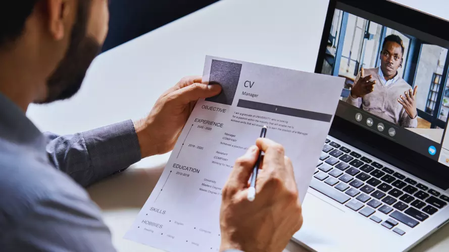 Man reviews a CV while talking online with a candidate 