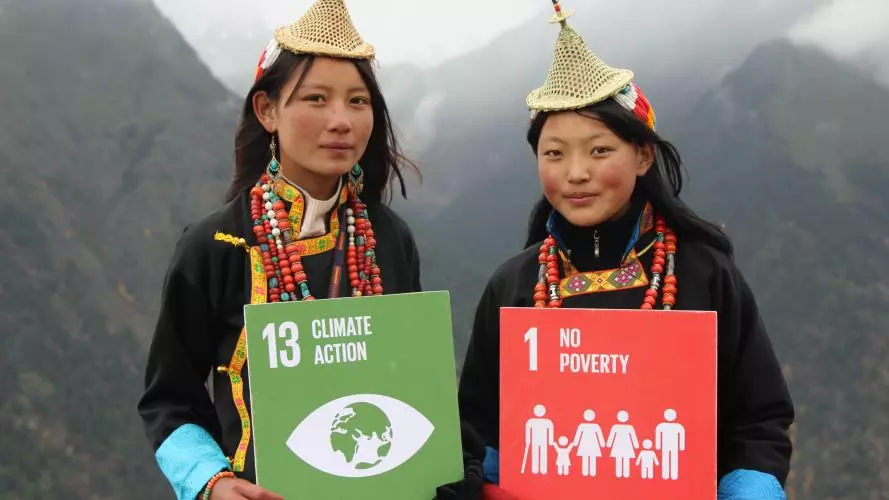 Two people holding signs which read '13 Climate Action' and '1 No Poverty'. Photo: UNDP Bhutan