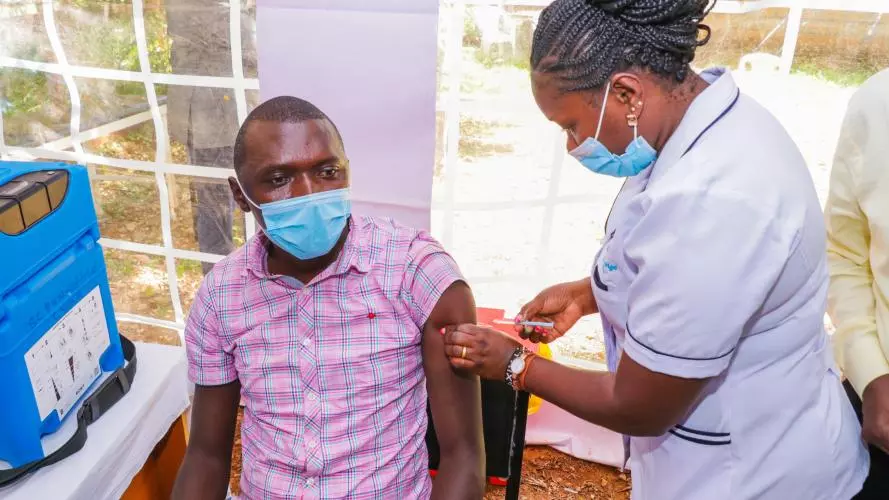 A female nurse gives a man an injection at an outdoor hospital