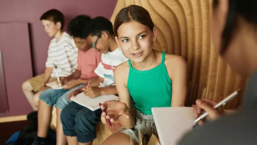 Image of teenagers studying while sitting on a sofa