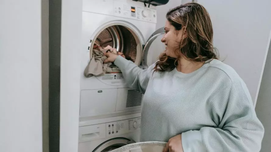 Image of a woman loading a washing machine