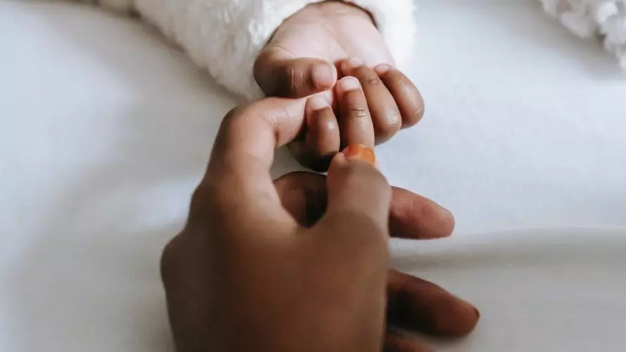 Close up of mother holding her baby's hand