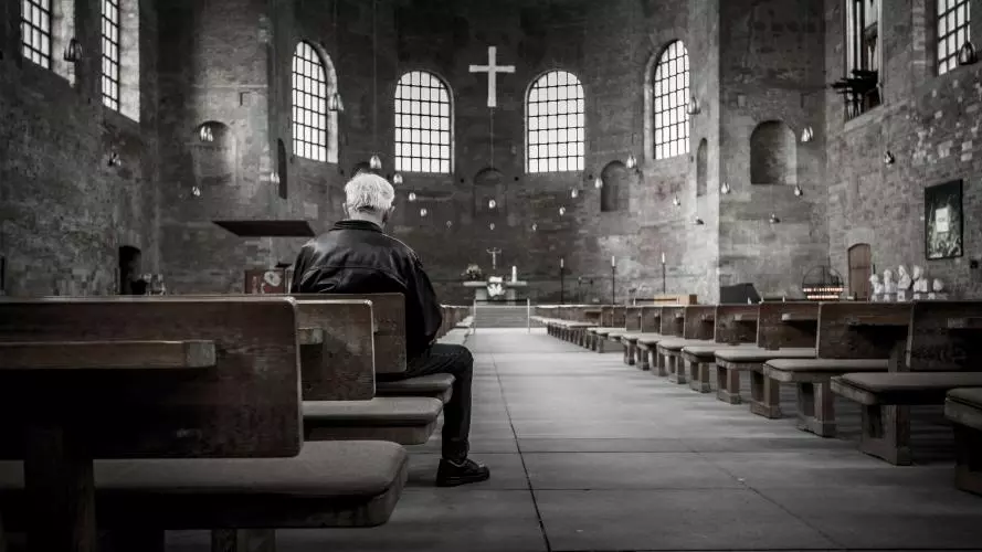 Image of lone man sitting in a church 
