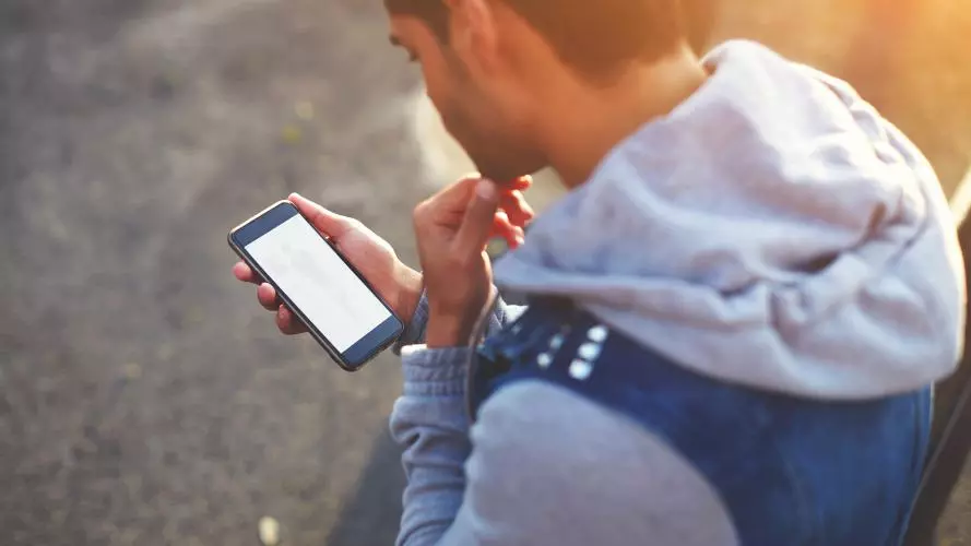 A teenager looking at a phone. Photocredit Shutterstock