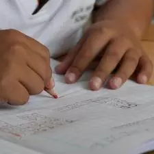 A child drawing in pencil in a notebook