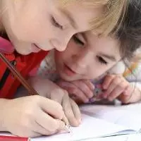 Two children writing in a school book.