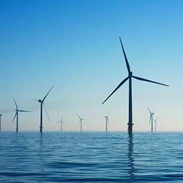 Wind farm at sea against a blue sky