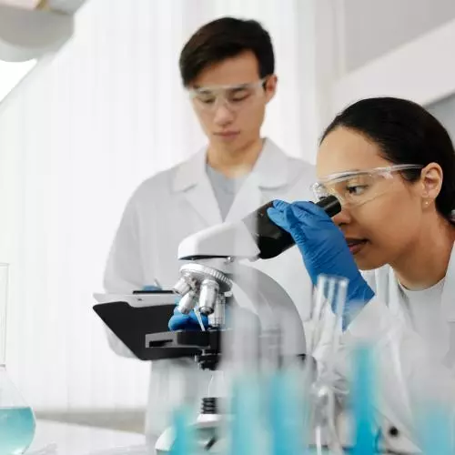 Male and female scientists look at a microscope 