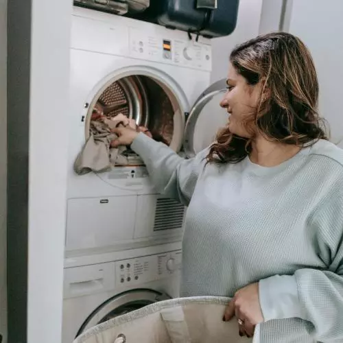 Image of a woman loading a washing machine