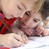Two children writing in a school book.