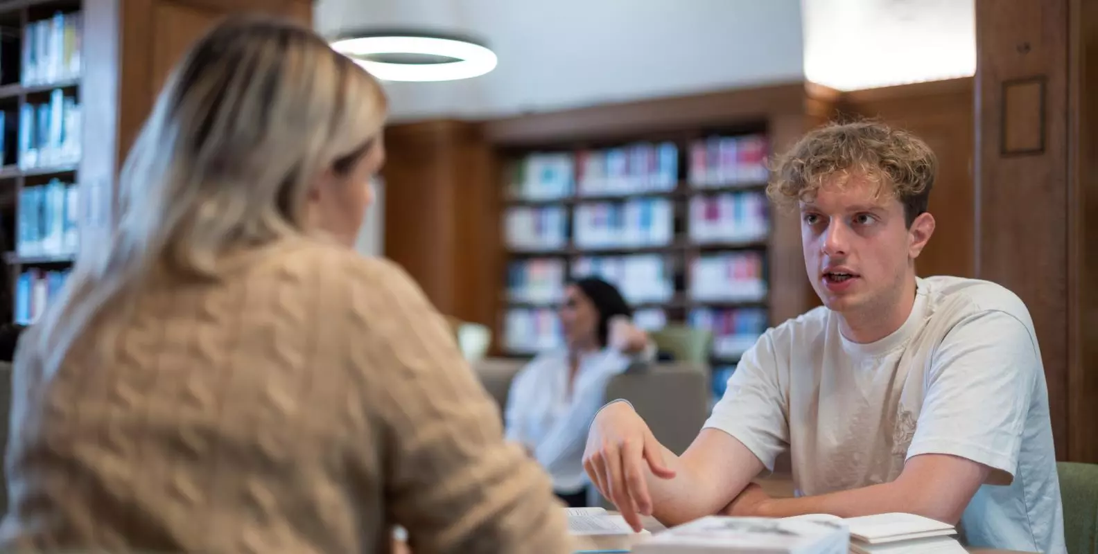 Image of two students working in a library 