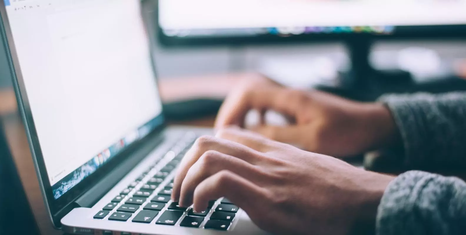 Hands typing on a laptop keyboard