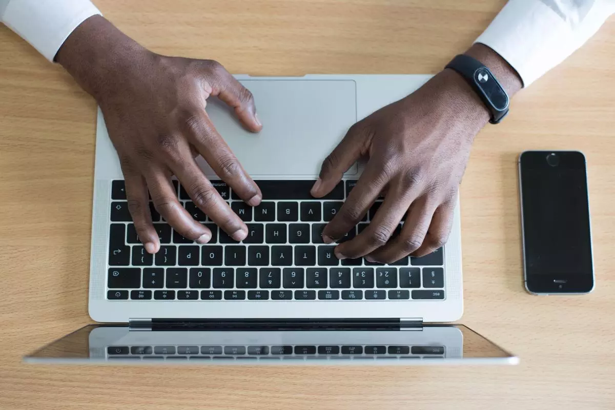 A man's hands type of a laptop keyboard